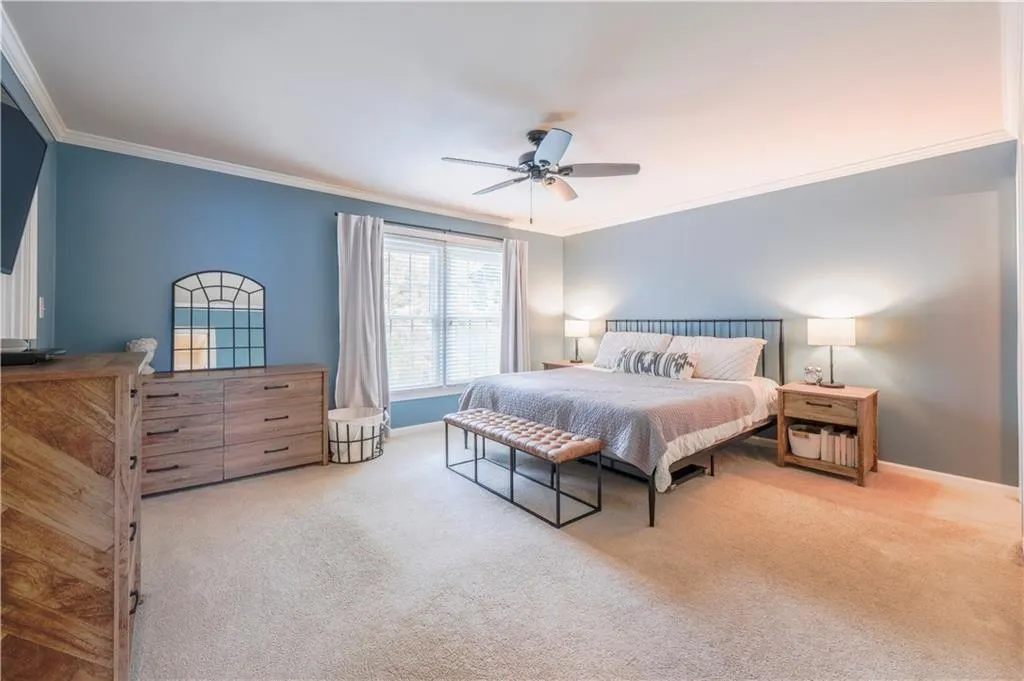 Carpeted bedroom featuring ornamental molding and a ceiling fan