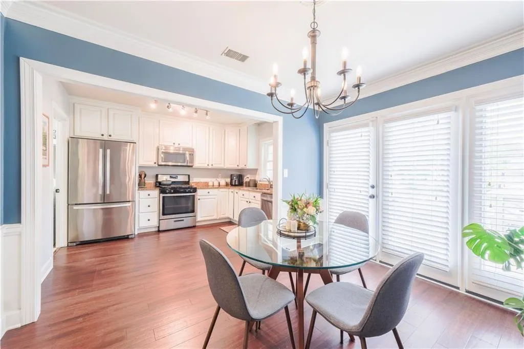 Dining area with a chandelier, light wood finished floors, ornamental molding, and rail lighting