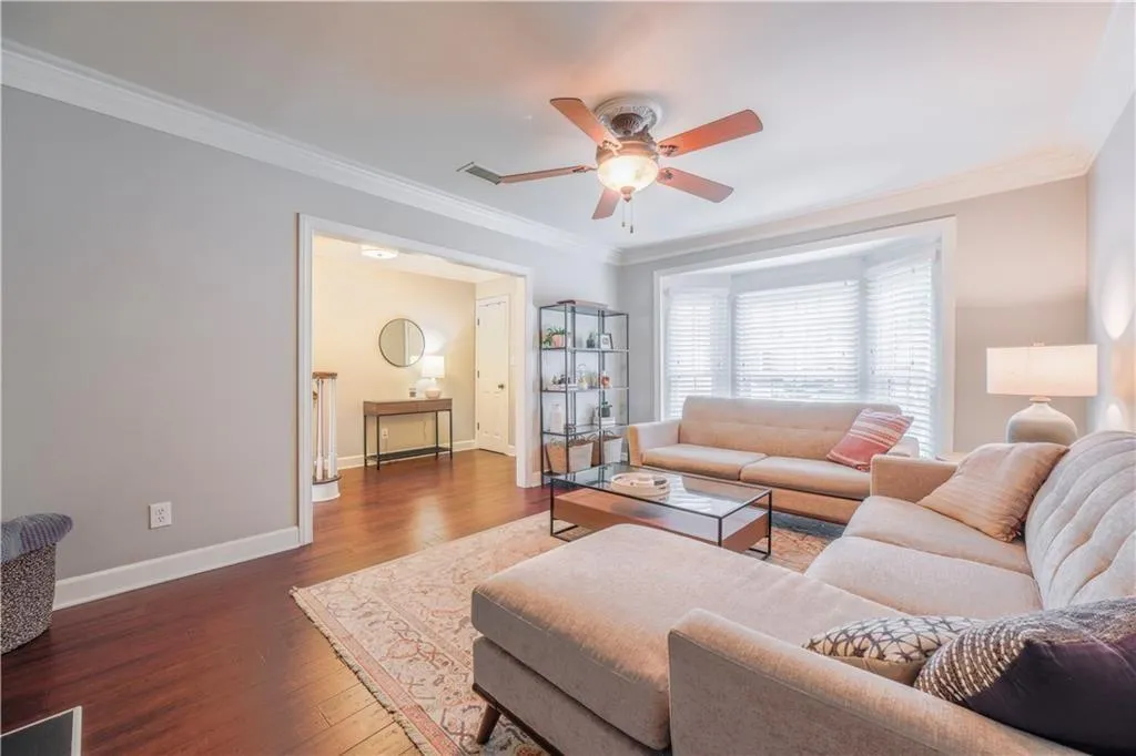 Living room with crown molding, hardwood / wood-style floors, and a ceiling fan