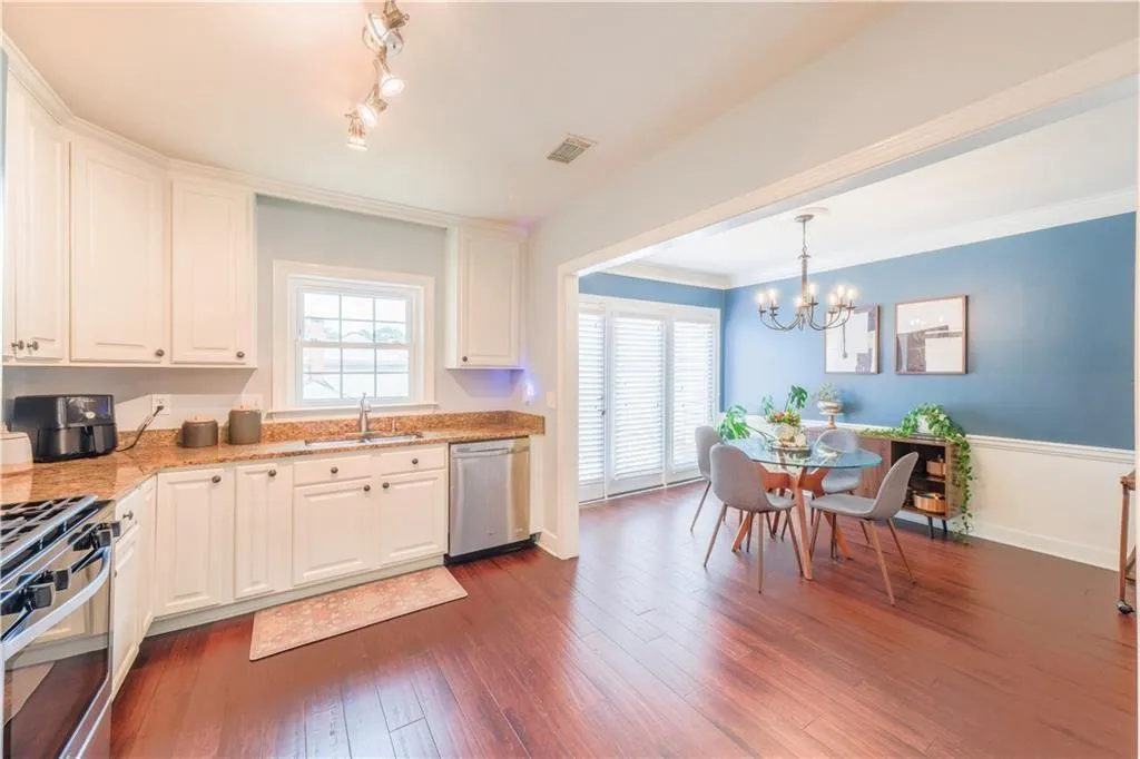 Kitchen with light stone counters, white cabinetry, healthy amount of natural light, and crown molding