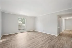 Unfurnished room featuring crown molding, wood finished floors, and baseboards