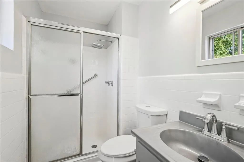 Full bathroom featuring wainscoting, a stall shower, vanity, and tile walls