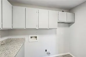 Laundry room featuring cabinet space, hookup for a washing machine, baseboards, electric dryer hookup, and wood finished floors