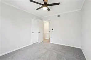 Spare room featuring ceiling fan, ornamental molding, carpet flooring, and baseboards