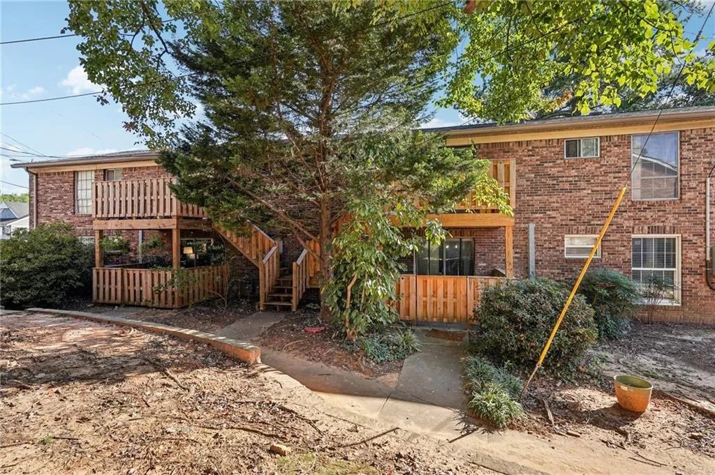 Rear view of property featuring a deck, brick siding, and stairs