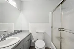 Full bathroom with toilet, vanity, and a stall shower