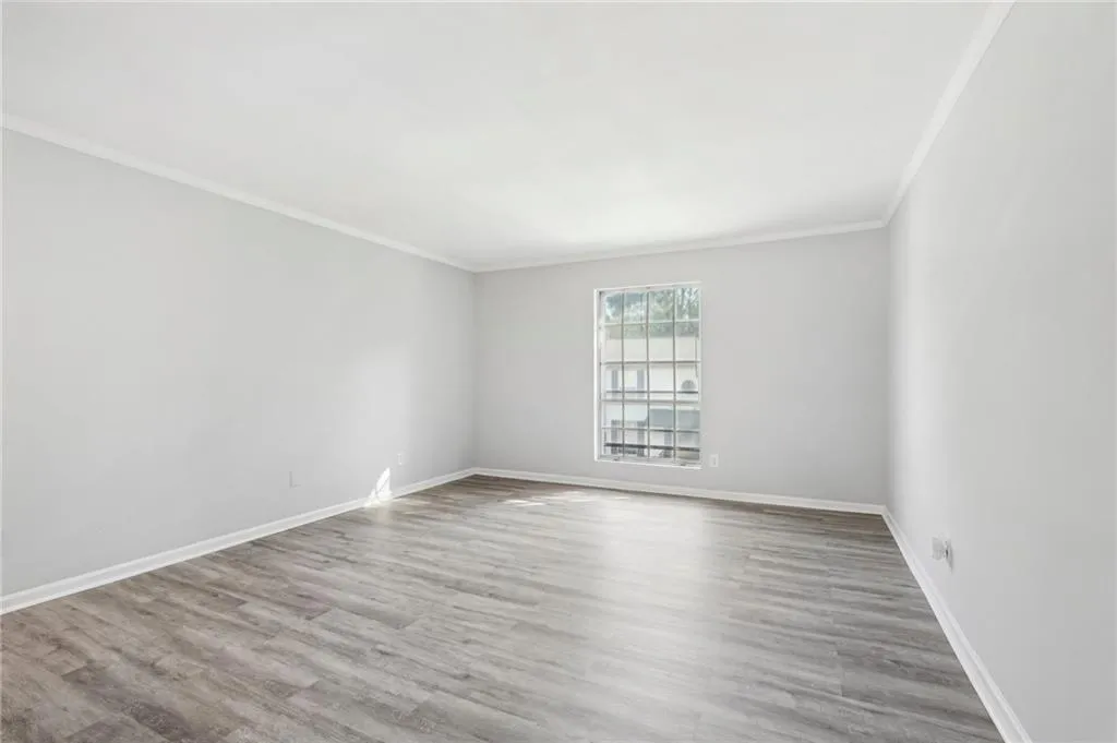 Empty room with crown molding, wood finished floors, and baseboards