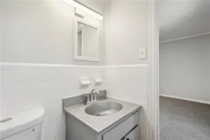 Bathroom featuring vanity, toilet, and wainscoting