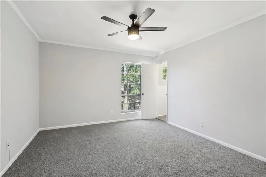 Empty room with ornamental molding, carpet floors, and ceiling fan