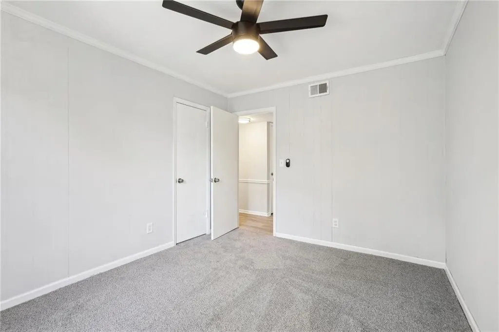 Unfurnished bedroom with crown molding, carpet floors, and a ceiling fan