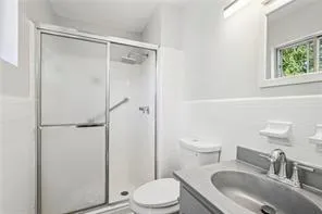 Bathroom featuring vanity, toilet, and a shower stall