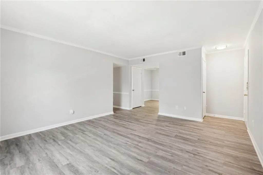 Unfurnished room with ornamental molding, wood finished floors, and baseboards