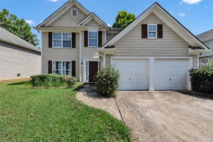 Siding exterior with decorative shutters, two-car garage, pitched roof, and a partial concrete driveway