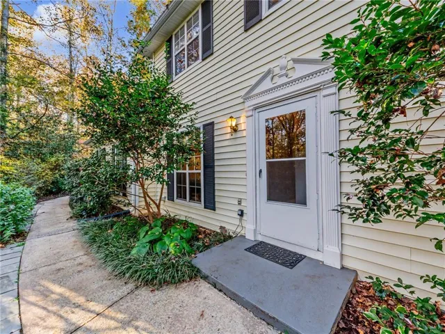 Elegant side entry featuring a white-painted door with glass panels, flanked by mature ivy and climbing greenery