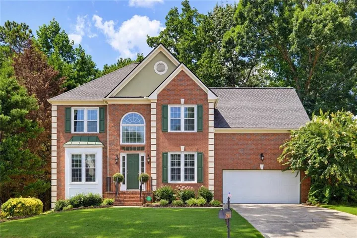 Brick facade with green shutters, arched window, and a two-car garage