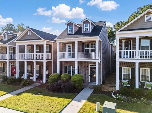 Brick and siding exterior with a dormer window, covered balcony, covered porch, and manicured landscaping