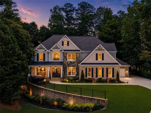 Stately two-story residence with a stone and brick façade, gabled rooflines, and a covered front porch