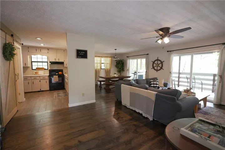 Open concept living area with wood-finish flooring, sliding glass doors, and a ceiling fan with integrated lighting