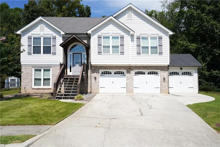 Split-level residence featuring a brick and siding exterior, arched front entry with an overhanging portico, and a three-car garage