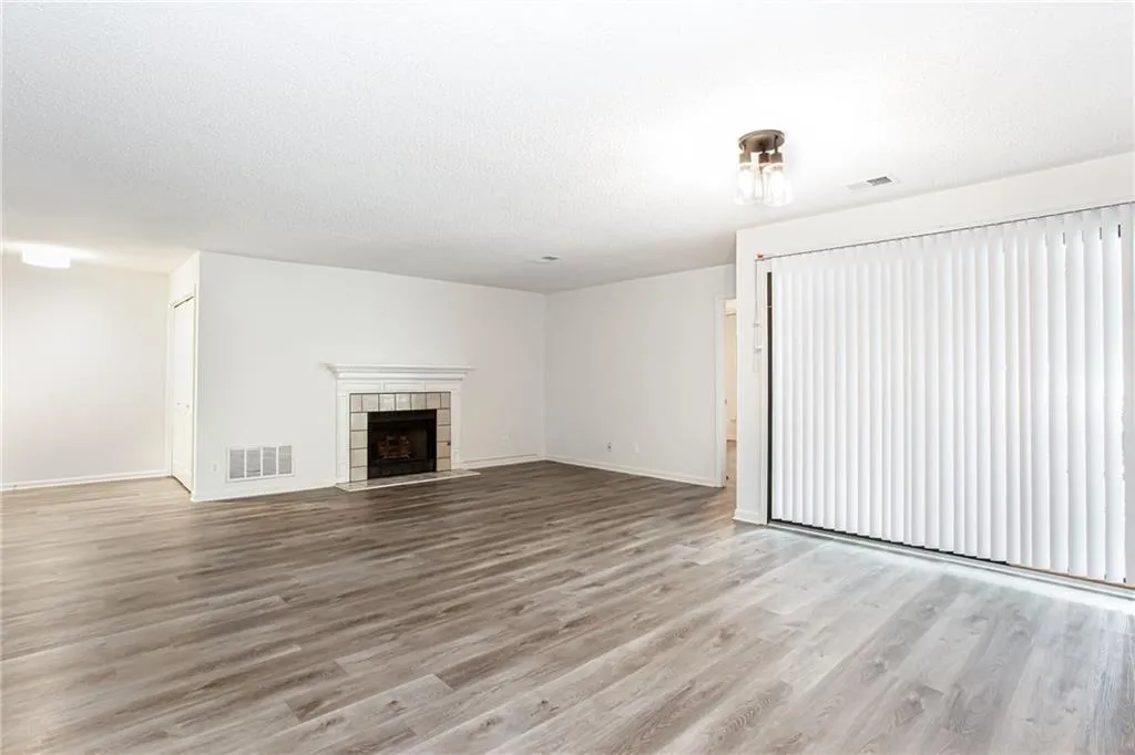 Unfurnished living room featuring light wood-style floors, a tile fireplace, and a textured ceiling