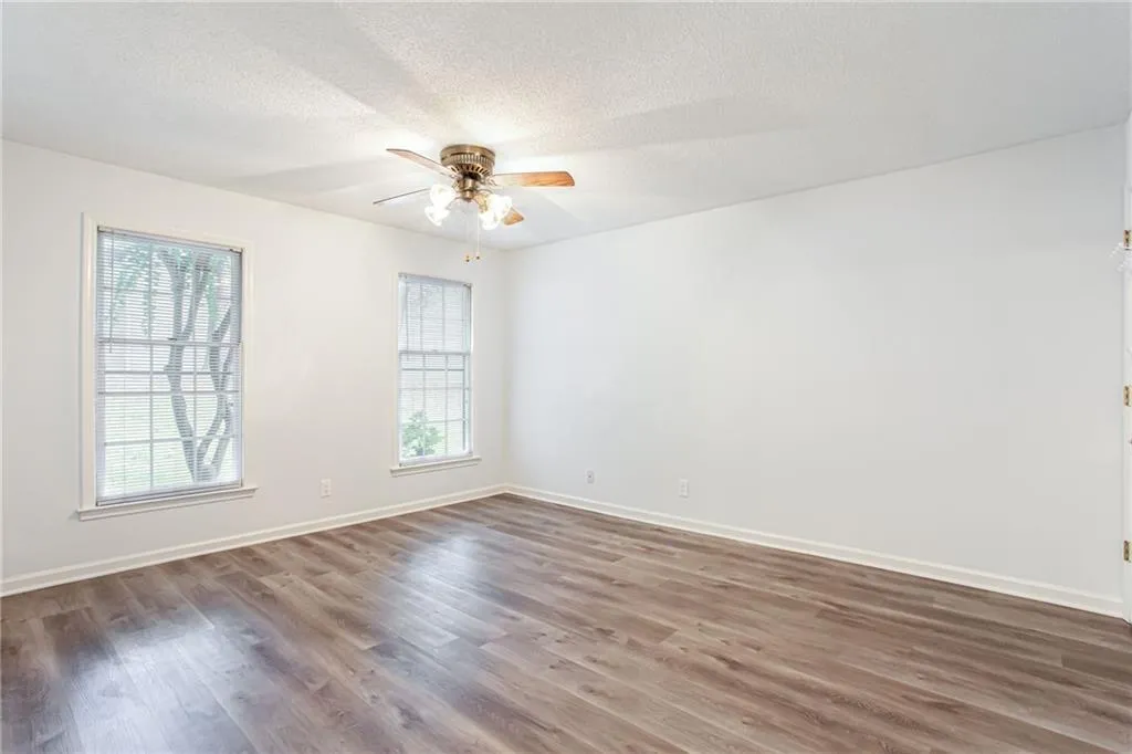 Unfurnished room with dark wood-style floors, a textured ceiling, and a ceiling fan