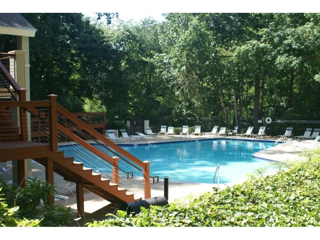 Community pool featuring a patio area, stairs, and view of scattered trees