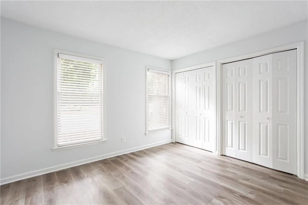 Unfurnished bedroom with multiple closets, a textured ceiling, and light wood-style floors