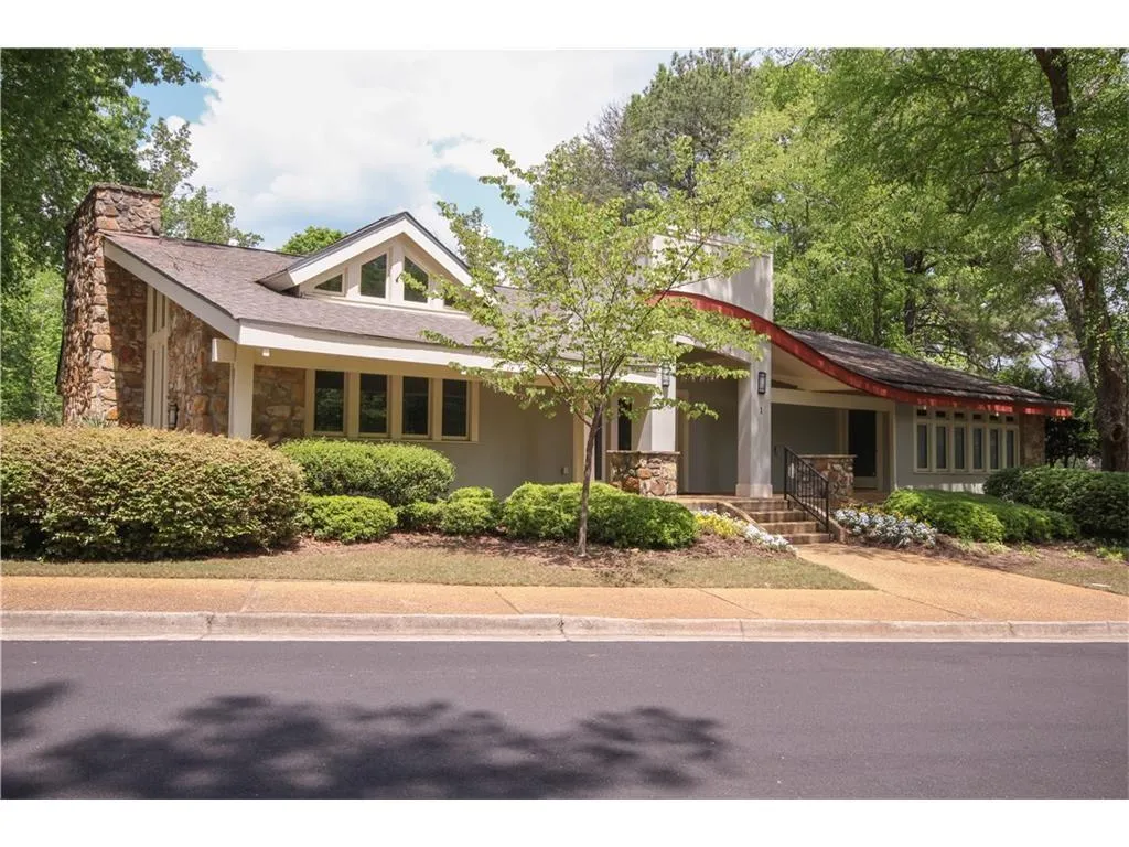 View of front facade featuring stone siding, covered porch, a chimney, and stucco siding