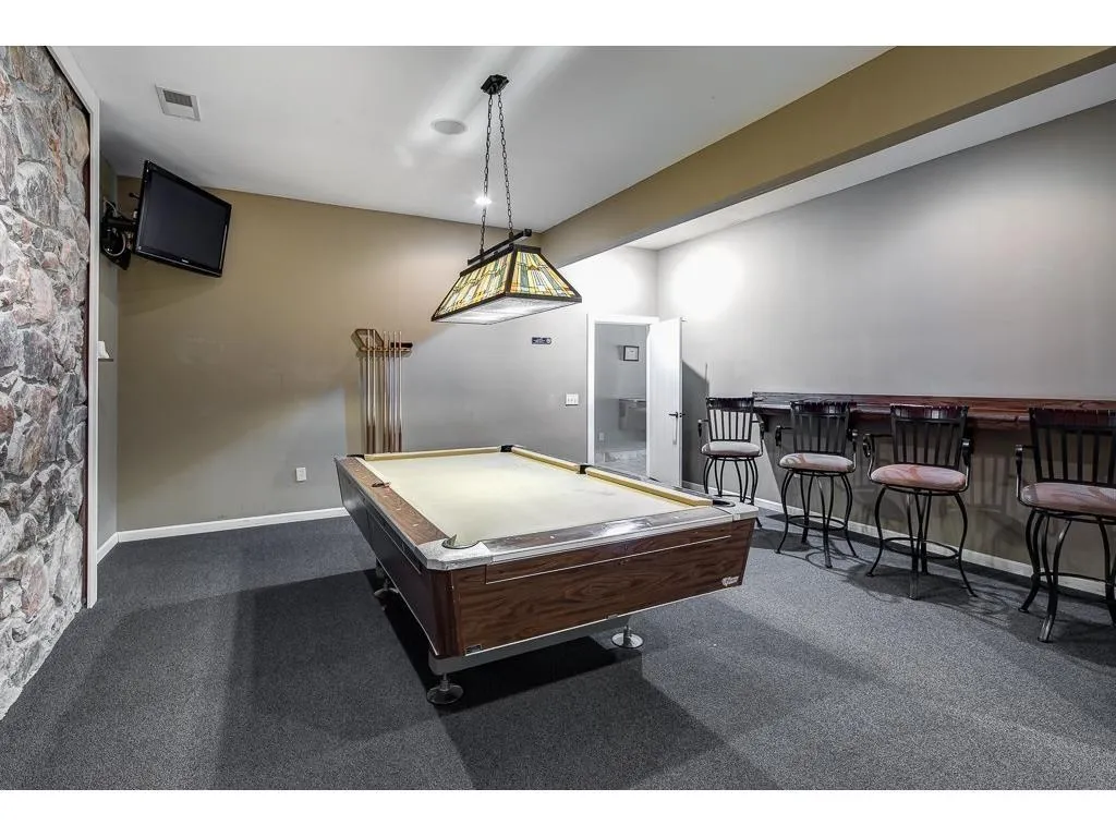 Recreation room featuring dark colored carpet, pool table, and a dry bar