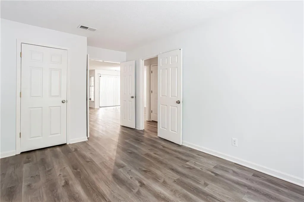 Unfurnished bedroom featuring dark wood-type flooring and baseboards