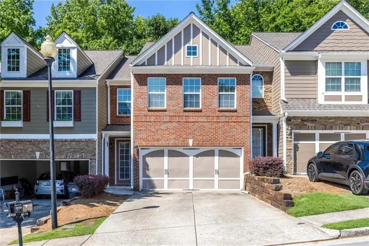 Brick and siding exterior featuring a two-car garage, dormer windows, and a front entry with glass paneling