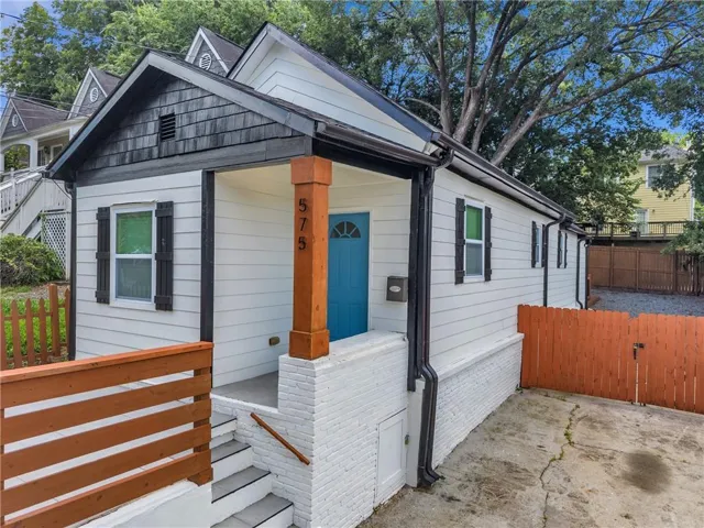 White siding exterior with a distinctive blue door and dark trim accents