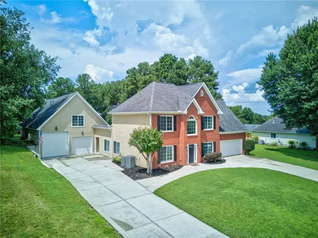 Two-story brick and siding exterior with multiple pitched roofs, an attached two-car garage, and an additional two-car garage structure