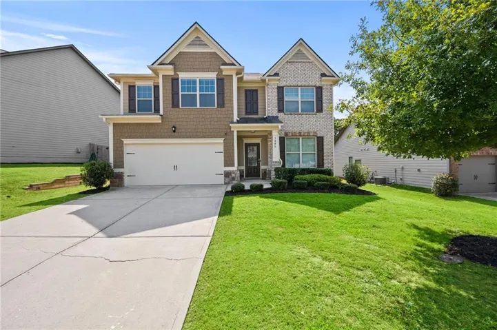 Two-story residence featuring a brick and siding exterior, an attached two-car garage, and a concrete driveway