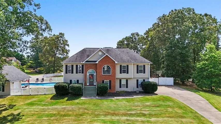 Two-story residence featuring a brick facade with arch window, light-colored siding, and a dark roof