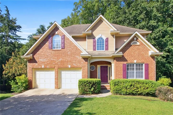 Traditional-style home featuring driveway, an attached garage, and brick siding
