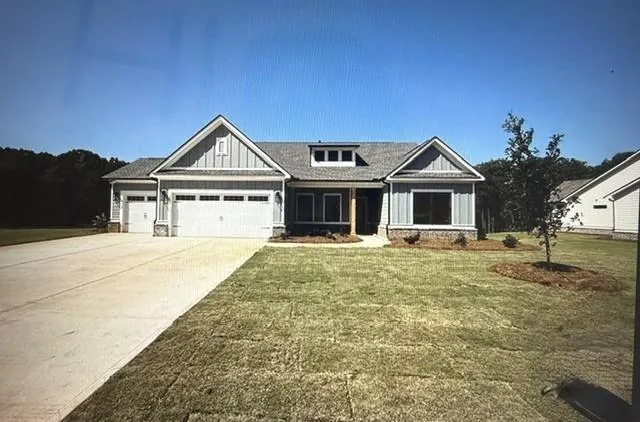 Light gray siding exterior with stone accents, a two-car garage, a single-car garage, and a dormer window