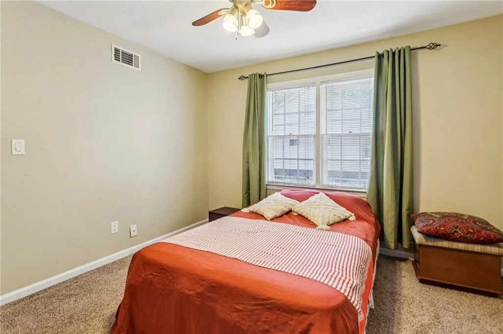 Carpeted bedroom with ceiling fan and baseboards