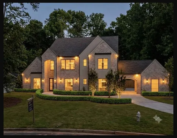 Stone and stucco exterior with dark-frame windows, a paved driveway, and an arched entryway