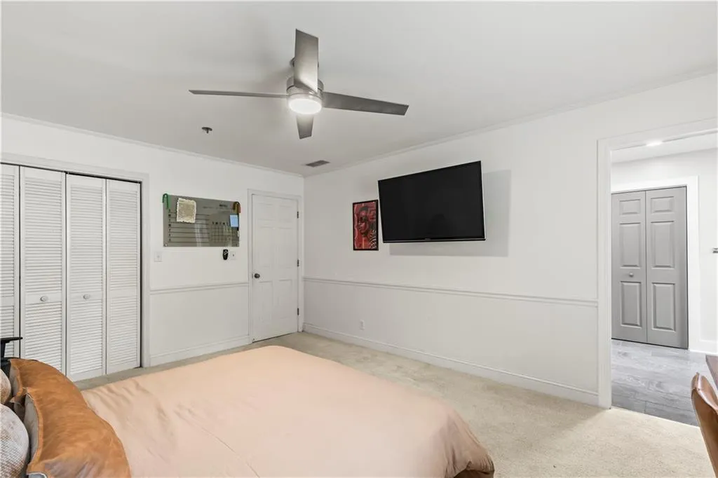 Bedroom featuring light colored carpet, a ceiling fan, ornamental molding, and a closet