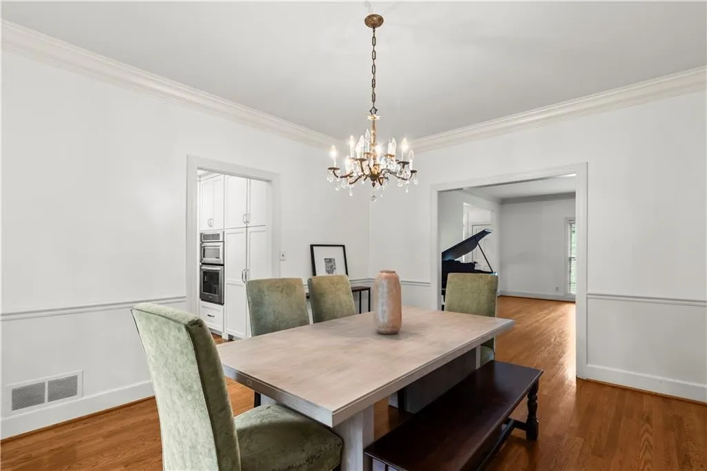 Dining room with crown molding, dark wood-style flooring, and a chandelier