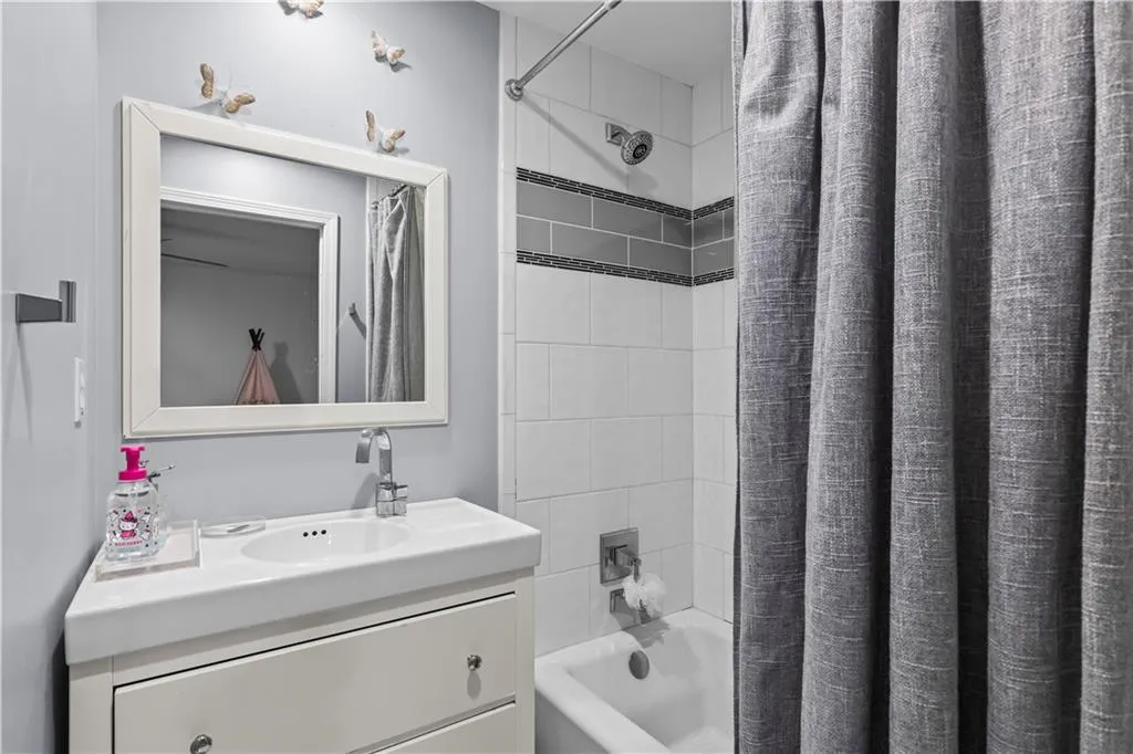 Bathroom featuring shower / bath combination with curtain and vanity