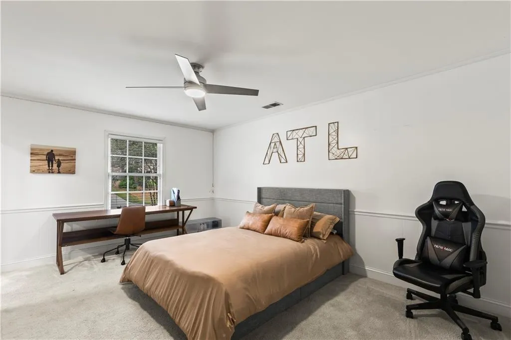 Carpeted bedroom featuring a desk, ornamental molding, and ceiling fan
