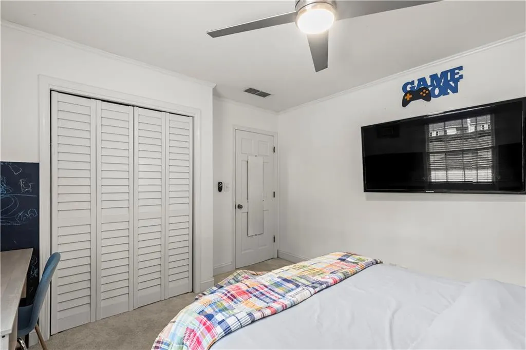 Carpeted bedroom with ornamental molding, a ceiling fan, and a closet