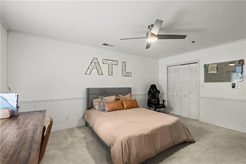 Bedroom featuring light carpet, a ceiling fan, a closet, and crown molding