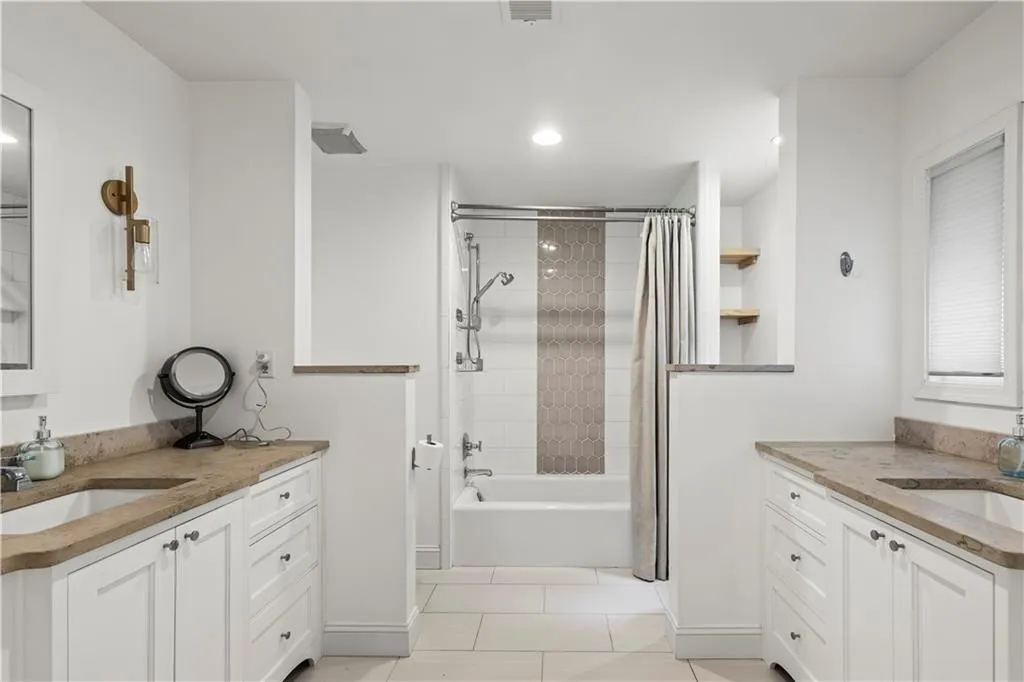 Bathroom with two vanities, shower / bath combo with shower curtain, light tile patterned flooring, and recessed lighting