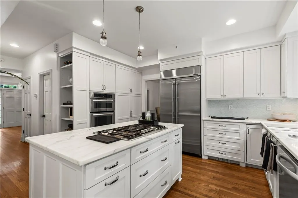 Kitchen with decorative light fixtures, open shelves, white cabinets, dark wood finished floors, and appliances with stainless steel finishes