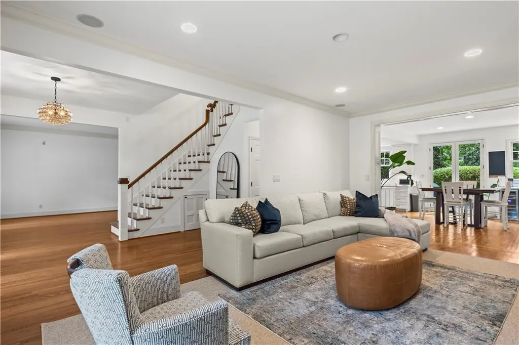 Living area with ornamental molding, wood finished floors, stairs, recessed lighting, and a chandelier