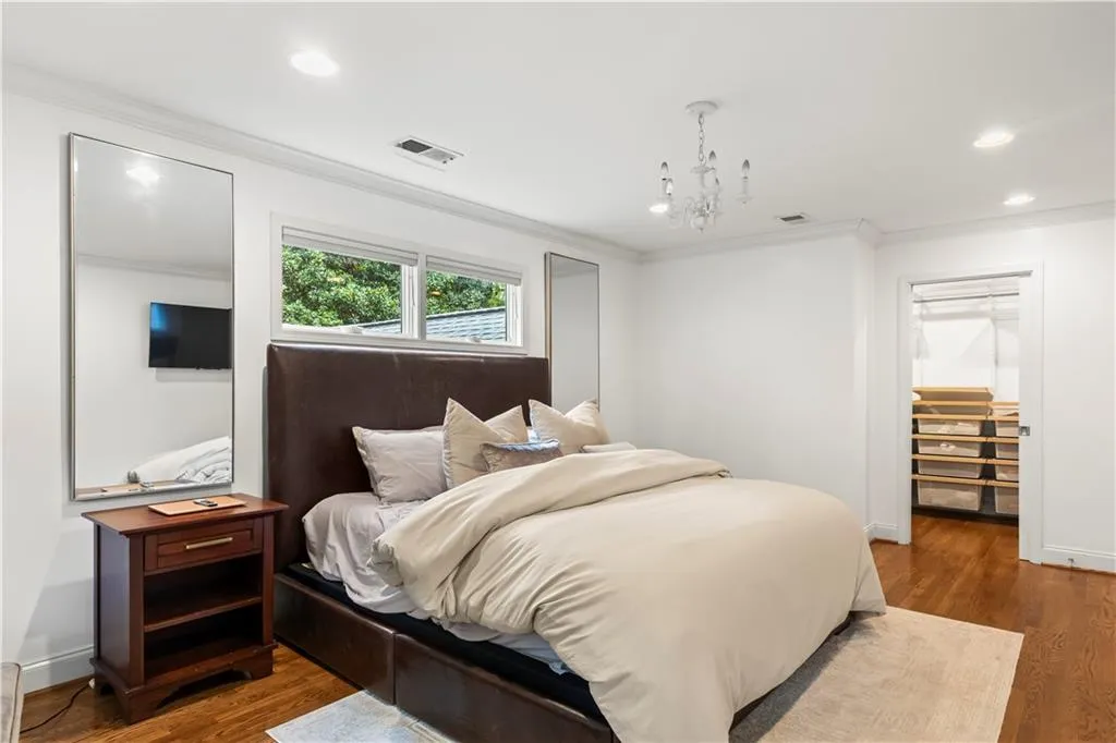 Bedroom featuring dark wood-type flooring, crown molding, a spacious closet, and recessed lighting