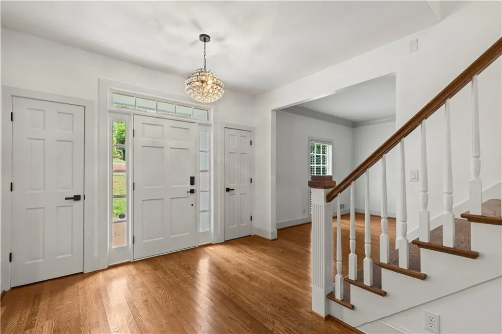 Entrance foyer with wood finished floors, a chandelier, and stairway